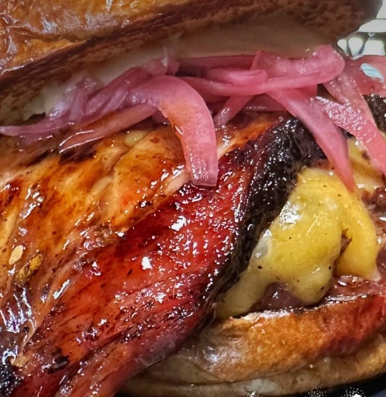 Hambúrguer N' Bacon com fatia grossa de pastrami bacon caramelizado, queijo derretido e picles de cebola roxa.